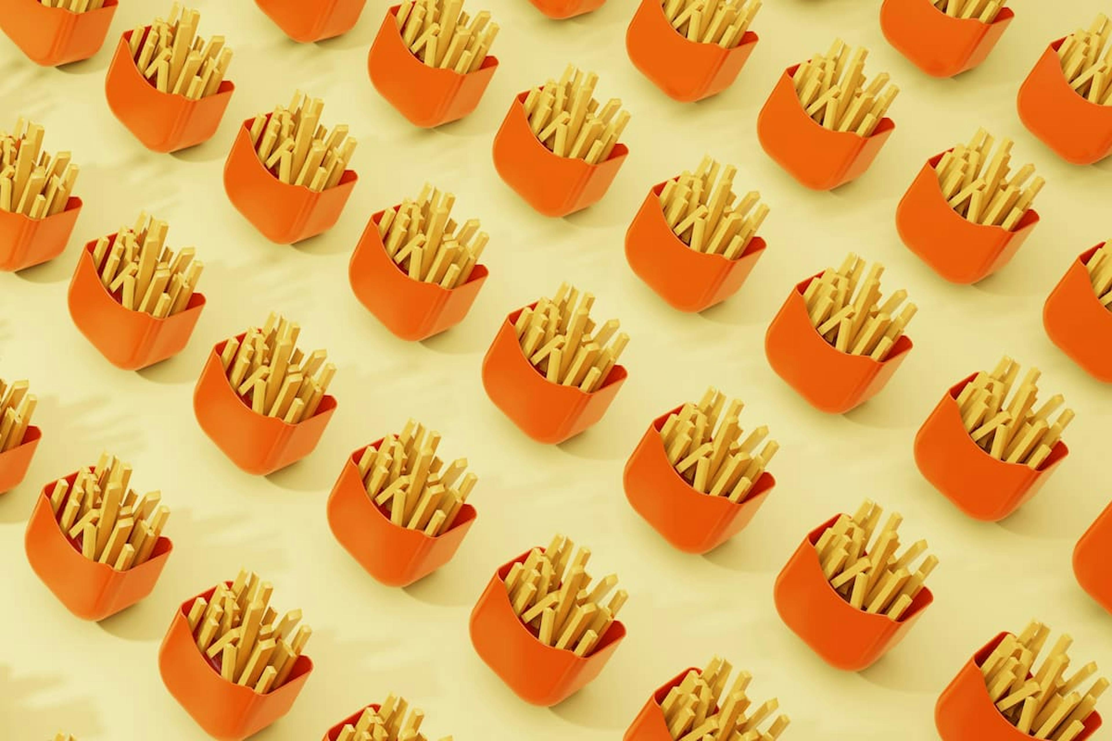 Multiple servings of French fries in bright orange containers arranged in a geometric pattern on a light yellow background.