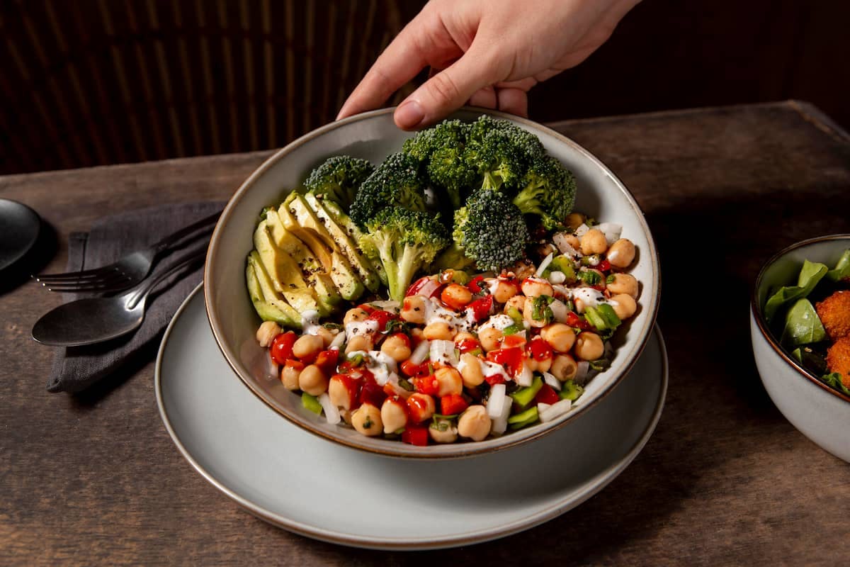 Colorful bowl with chickpeas, avocado, and broccoli showing how to provide vegan and vegetarian lunch options in the office.