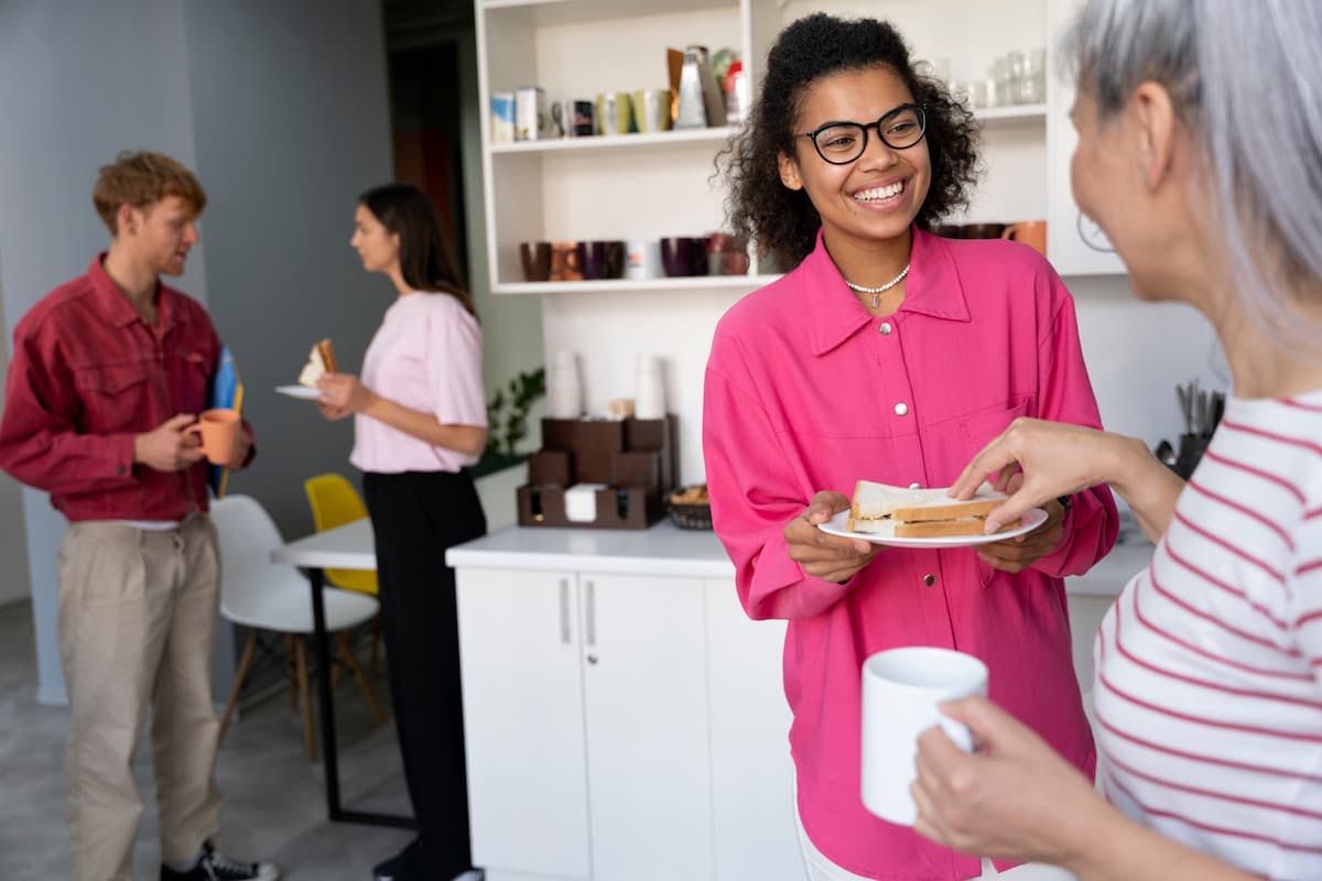 Employees enjoying snacks and conversations in a casual office setting showing the benefits of corporate catering with Picnic.