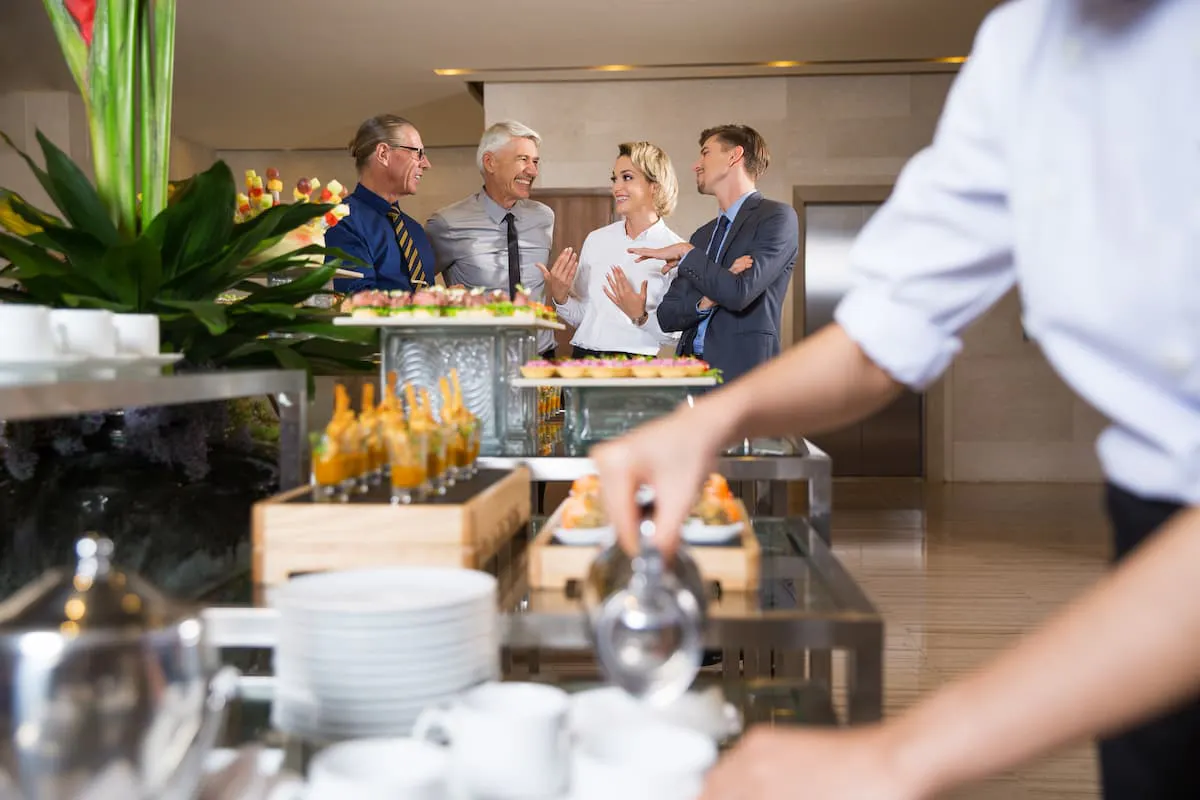 Professionals networking around food table showcasing benefits of corporate catering with Picnic for team bonding and relaxation.