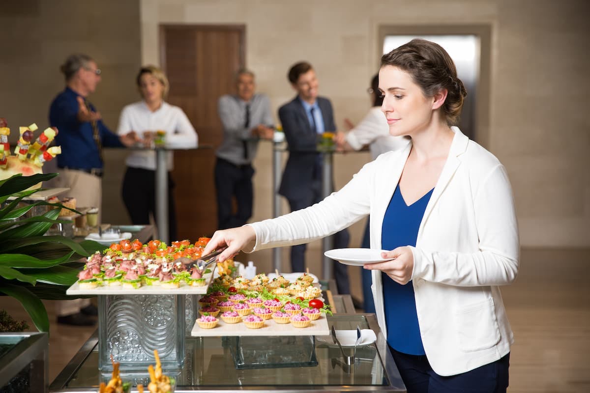 Professional woman choosing food at buffet, showing how to choose the right corporate catering service for business events.
