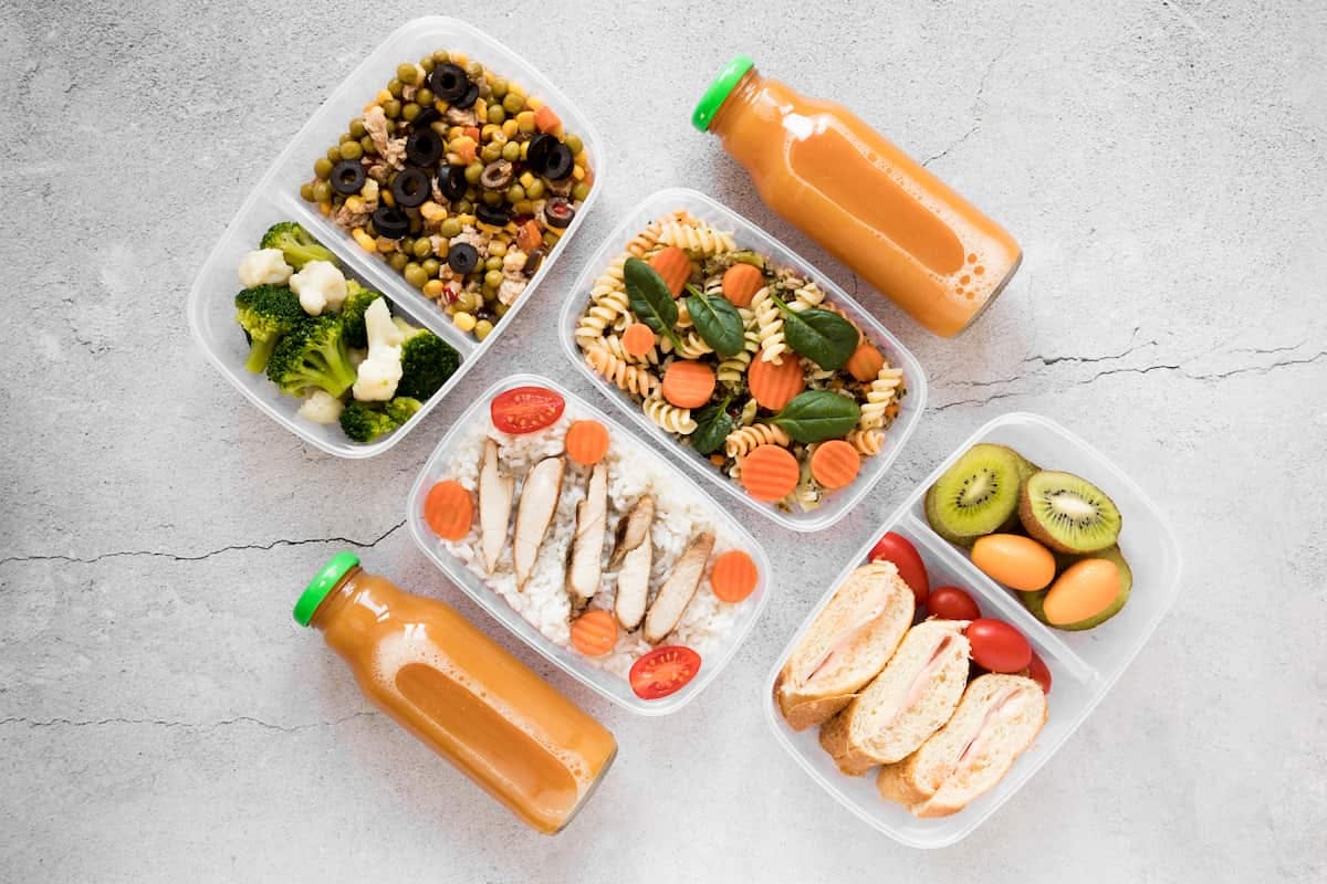 Four plastic containers filled with various foods, illustrating options for bulk meal orders.