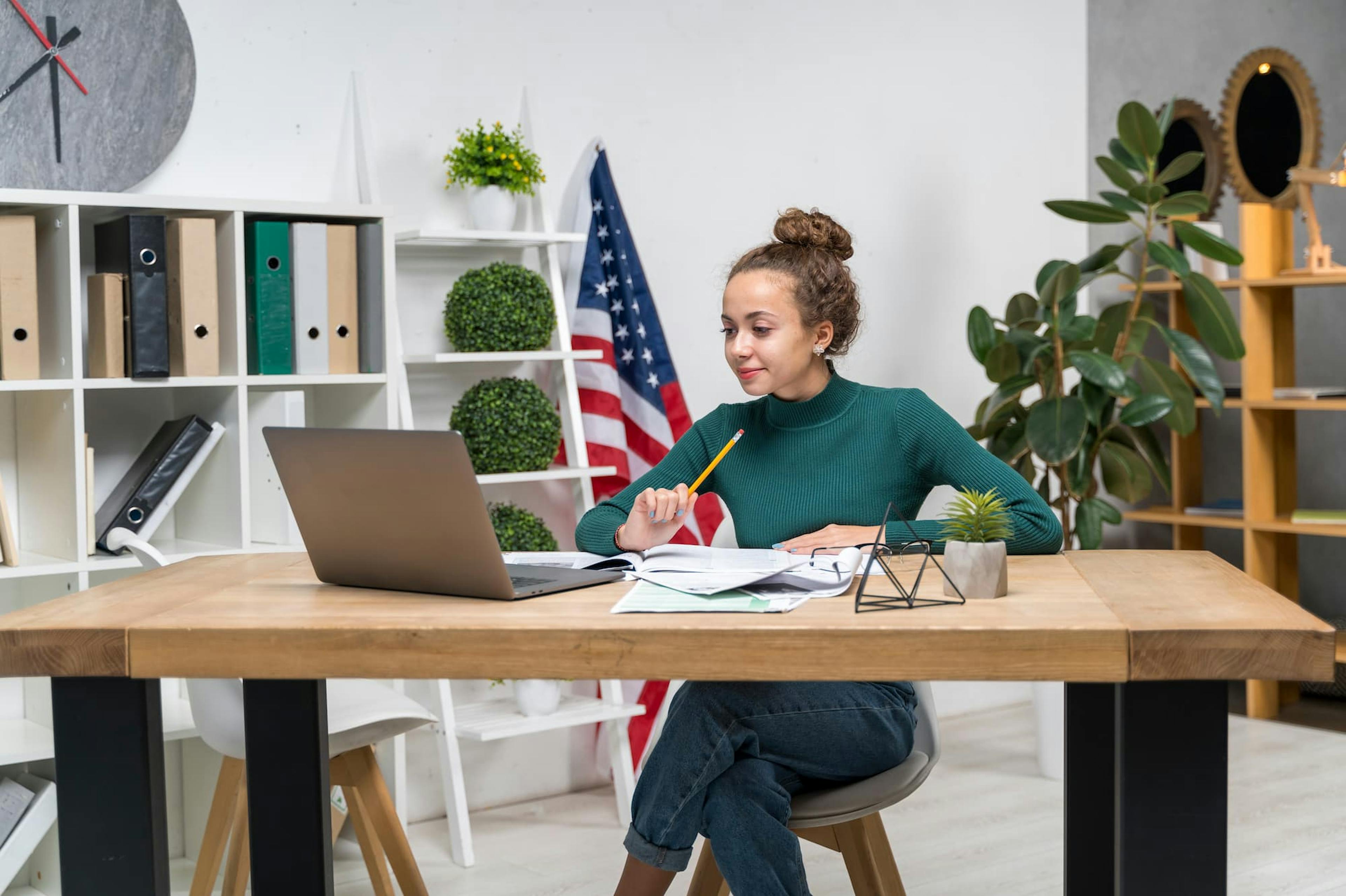 Woman working at a decorated desk with a U.S. flag, showing how to celebrate Independence Day at work with patriotism.