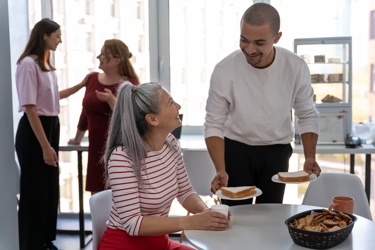 Coworkers sharing lunch and chatting, demonstrating how to create an employee meal experience that fosters connection and teamwork.