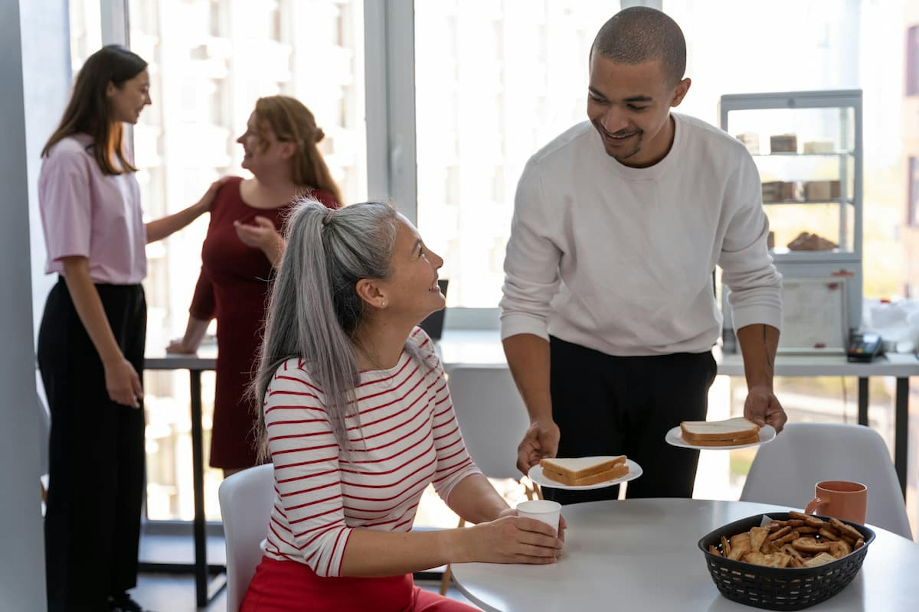 Coworkers sharing lunch and chatting, demonstrating how to create an employee meal experience that fosters connection and teamwork.