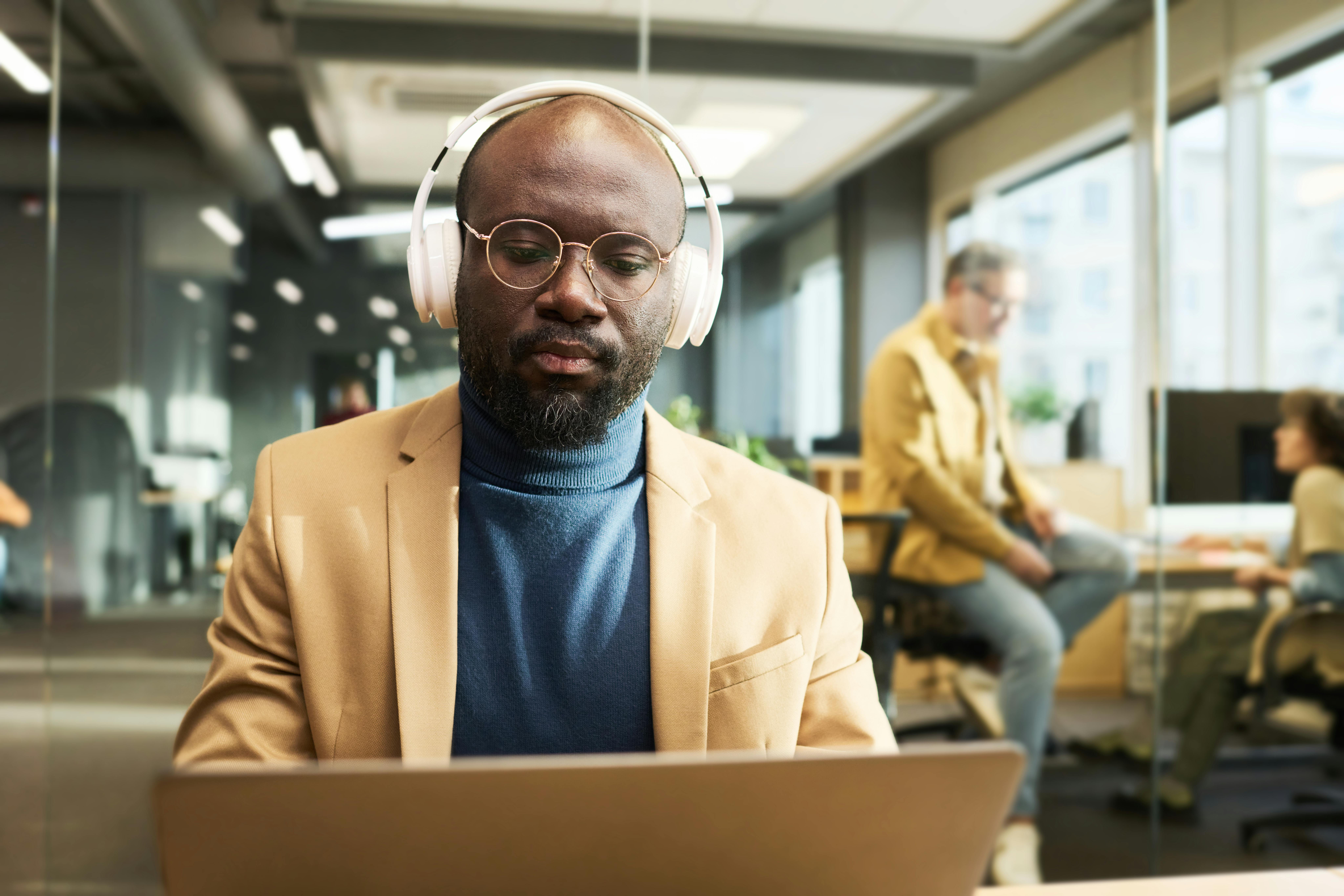 Man with headphones watching e-learning on his computer at work 