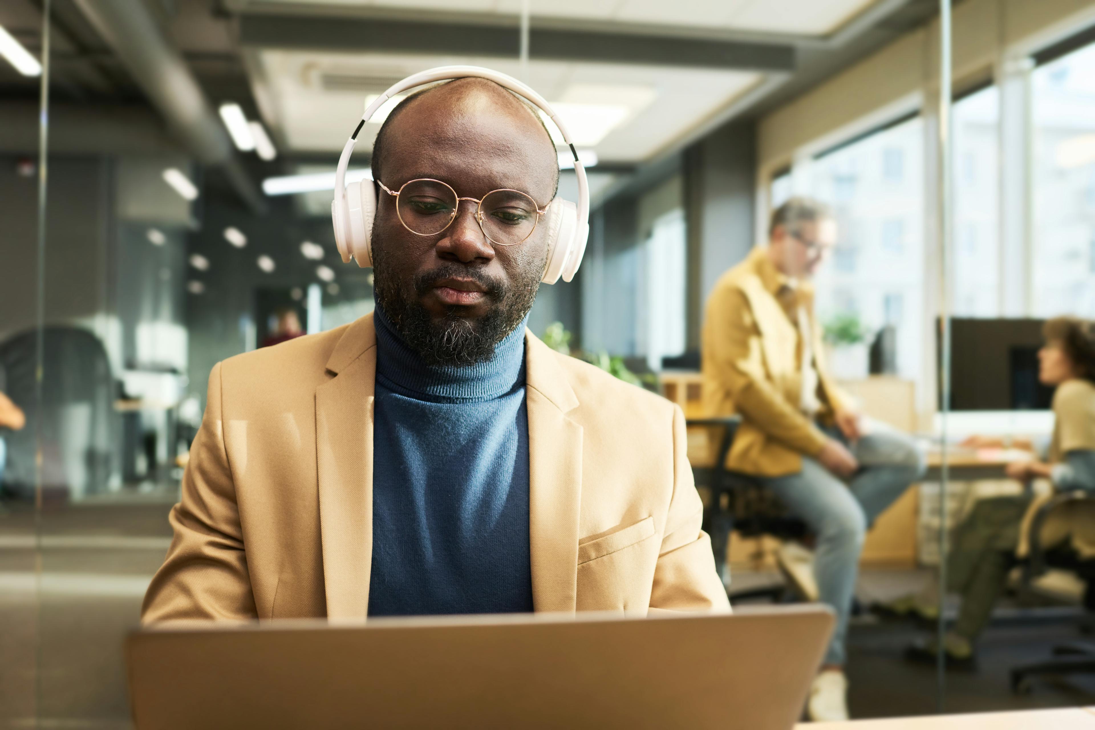 Man with headphones watching e-learning on his computer at work 