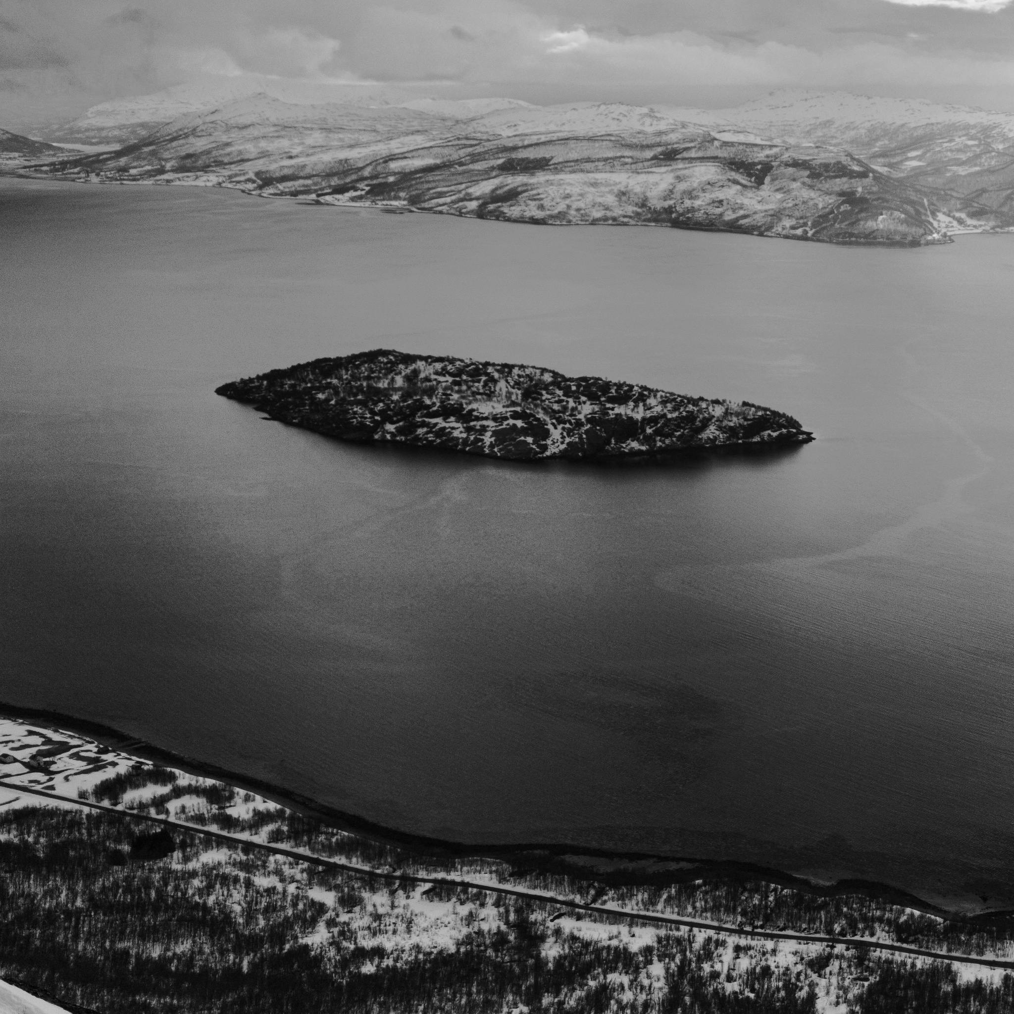 A black and white photo of an island in a fjord