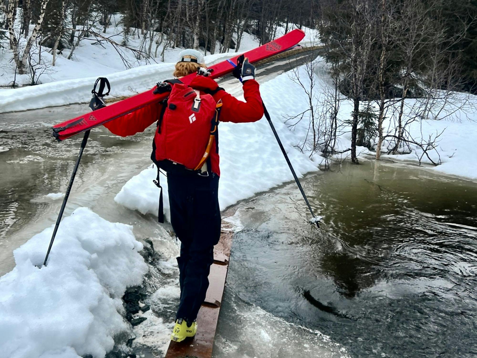 A skier crossing a plank over a river
