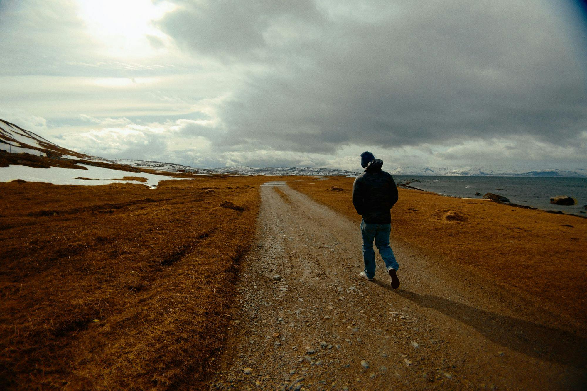 A man walking down an empty dirt road
