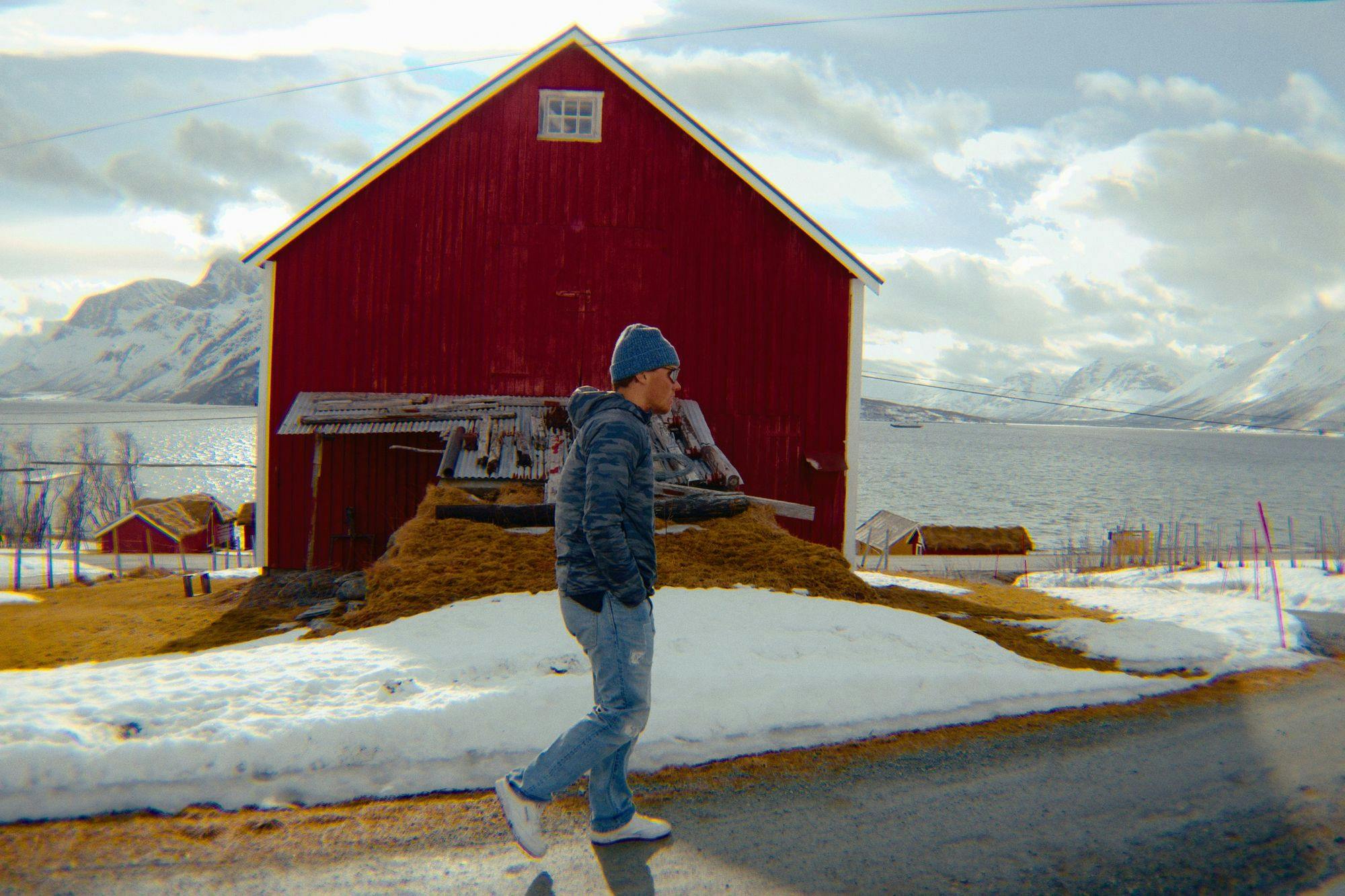 A man walking in front of a traditional red Norweigan farmhouse