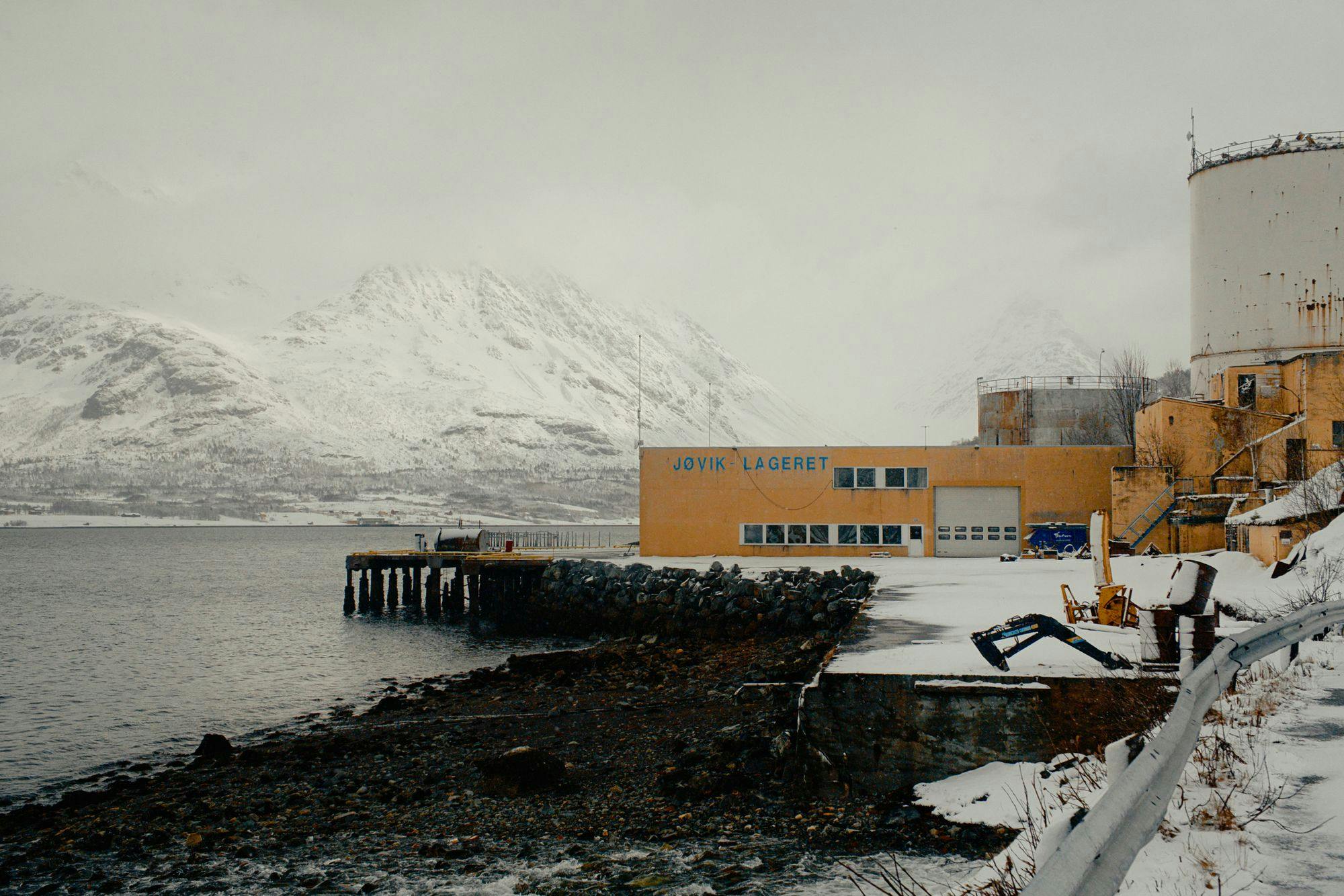 A decrepit industrial facility next to a fjord