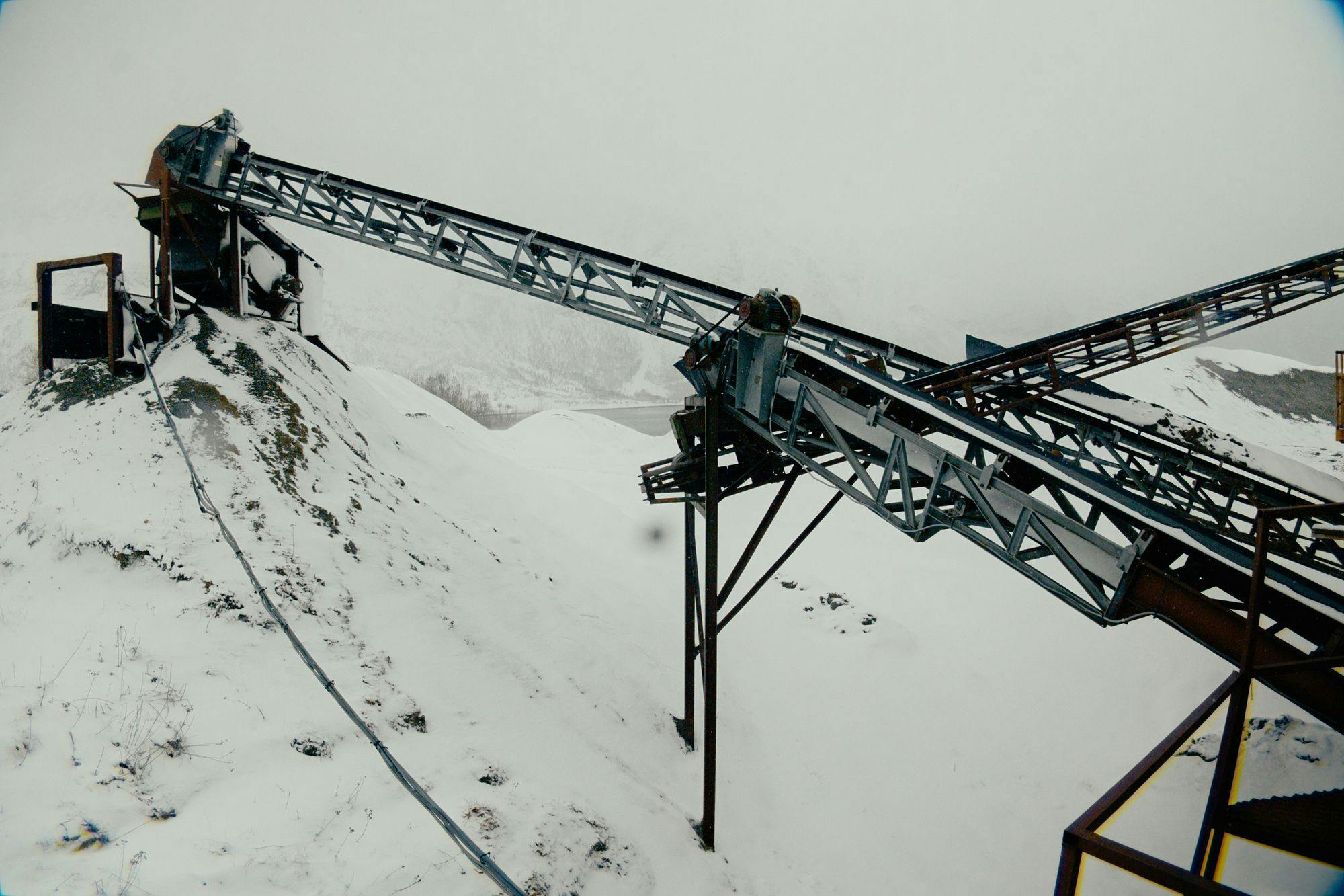 A decrepit industrial mining equipment covered in snow