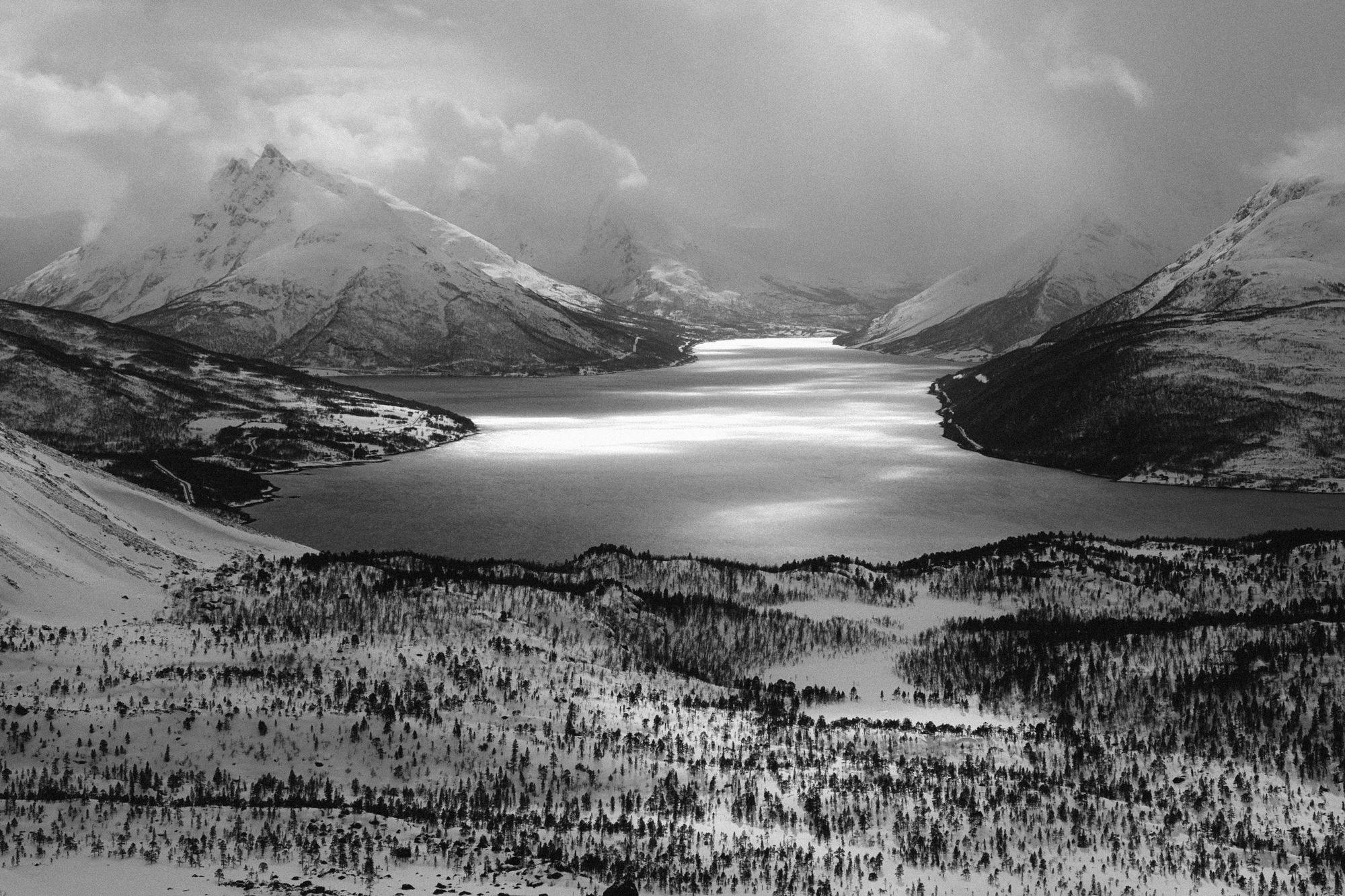 A black and white photo of a snowy fjord