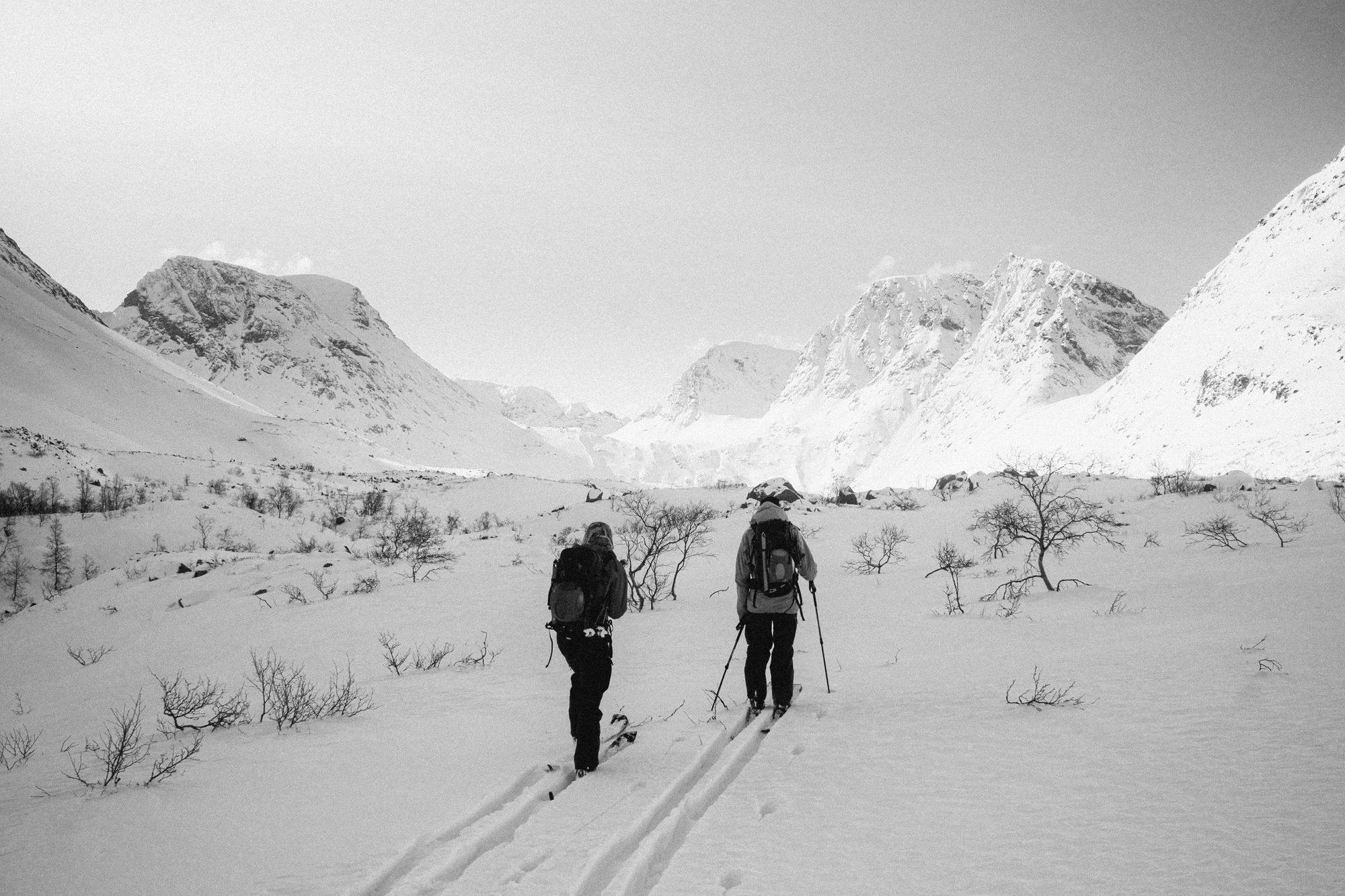 Two skiers walking through a vast valley