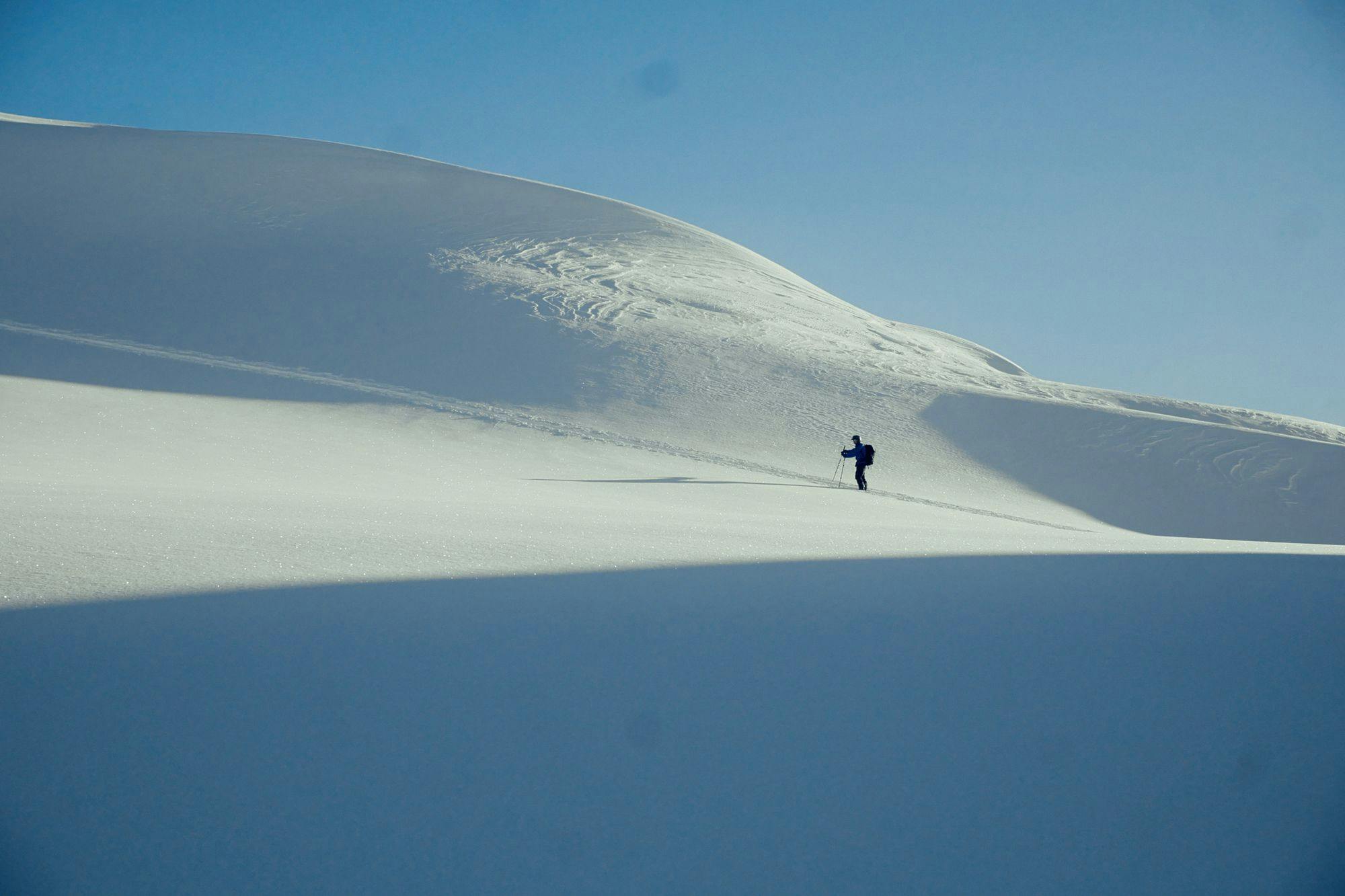 A skier crossing a blank white seciton of a mountain