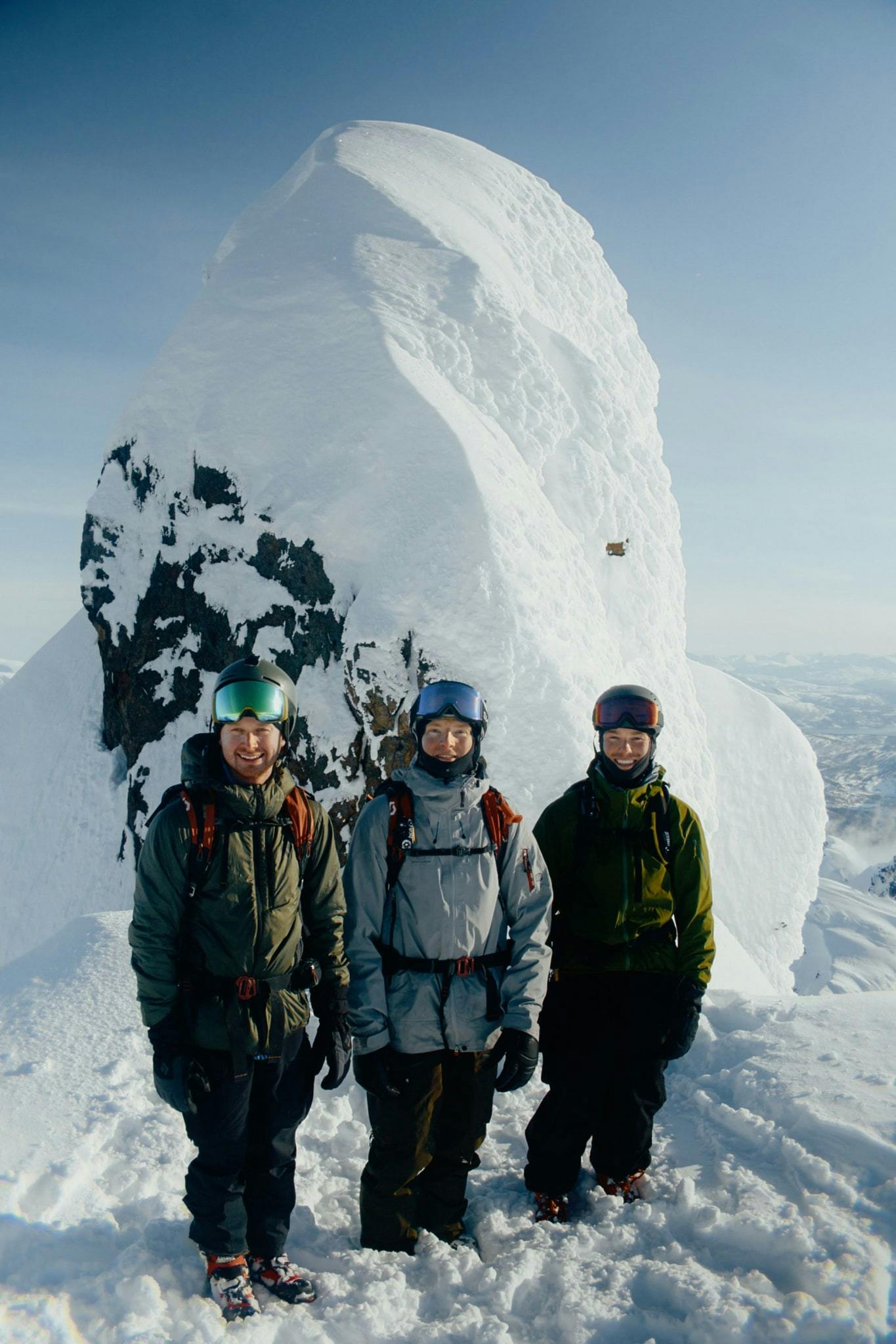 A portrait of three men from the summit of a peak