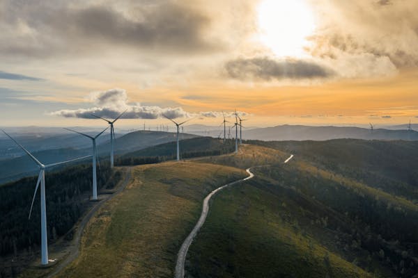 Windmolens op een heuvel met zon 