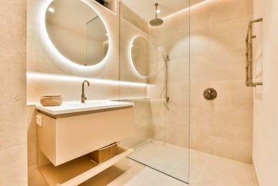 Badkamer van tegels met douche, wasbak en spiegel