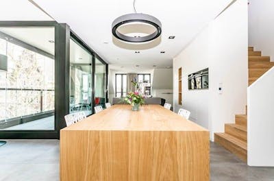 Woonkamer met houten eettafel en ramen 