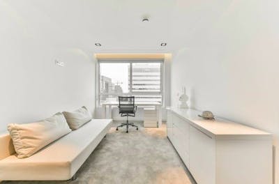 Kamer met bank en bureau en een wit interieur 