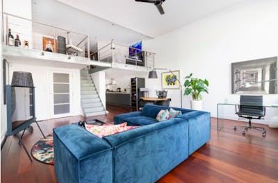 woonkamer met blauwe bank en glazen bureau 