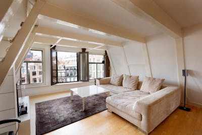 Woonkamer met bank, televisie en ramen 