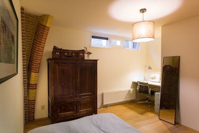 Kamer met bed, houten kast, spiegel en een bureau 