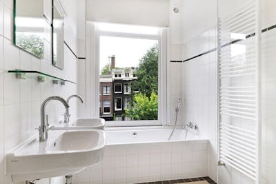 Badkamer met wasbakken, badkuip en raam