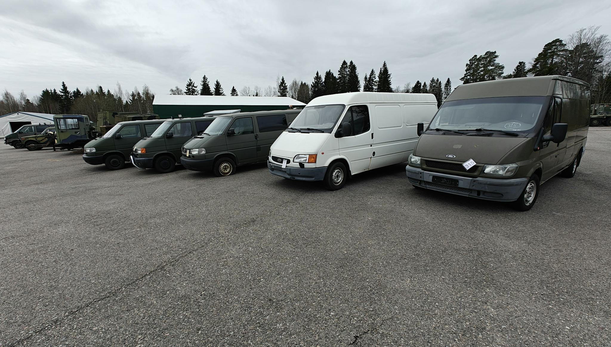 Puolustusvoimien huutokaupassa myytäviä pakettiautoja rivissä