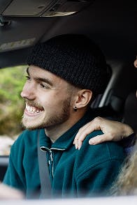 Hymyilevä nuori mies auton kyydissä