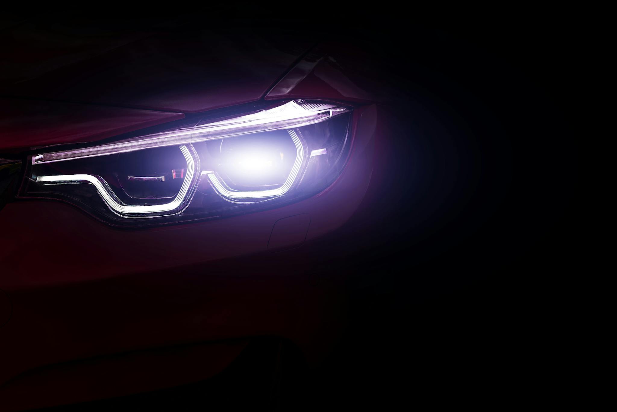 sähköauton etuvalot hohtavat pilkkopimeässä ulkona