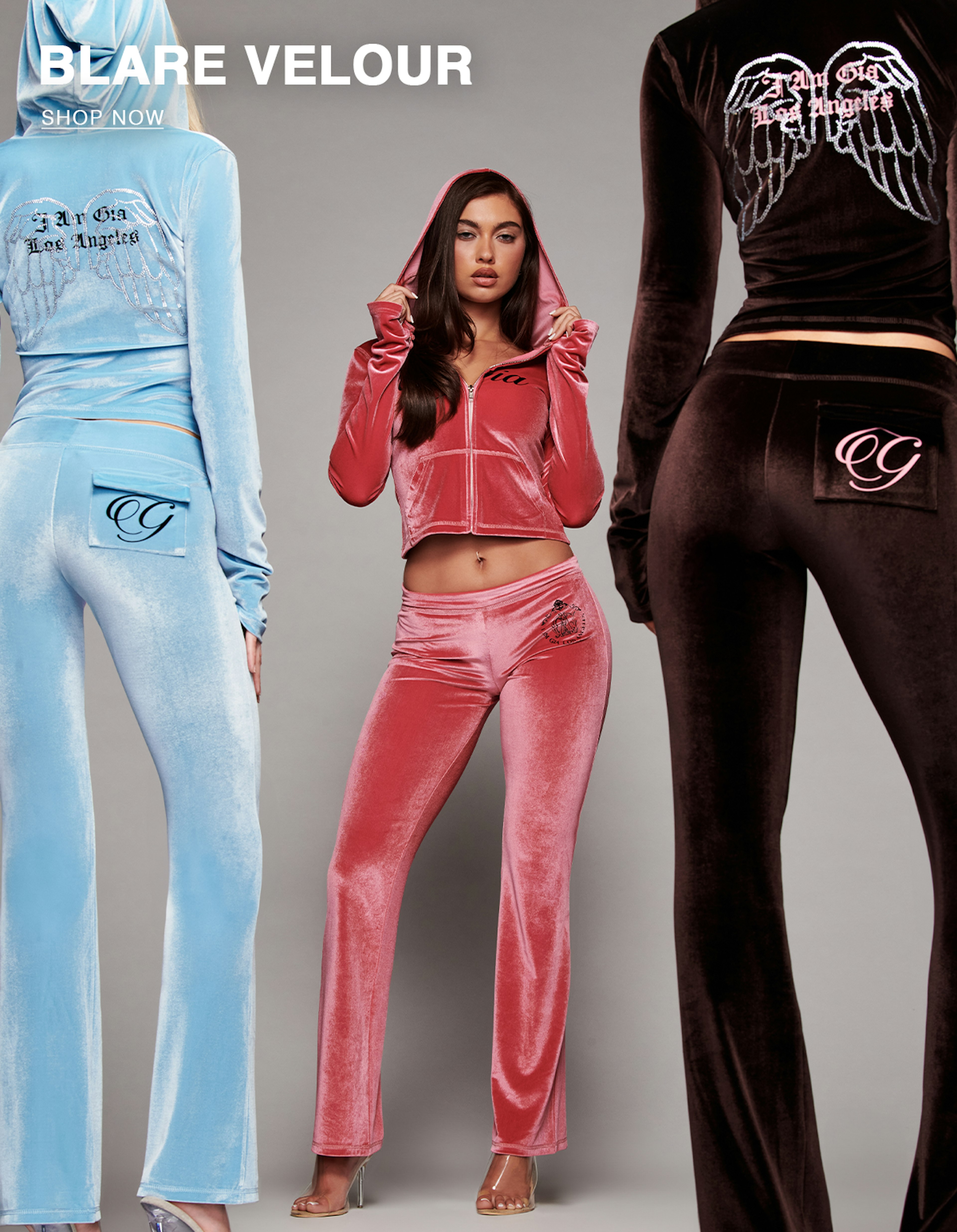 Three models wearing different colored velour tracksuits with visible branding on the front and back in front of a gray background.