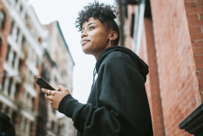 Woman smiling and holding a phone outside