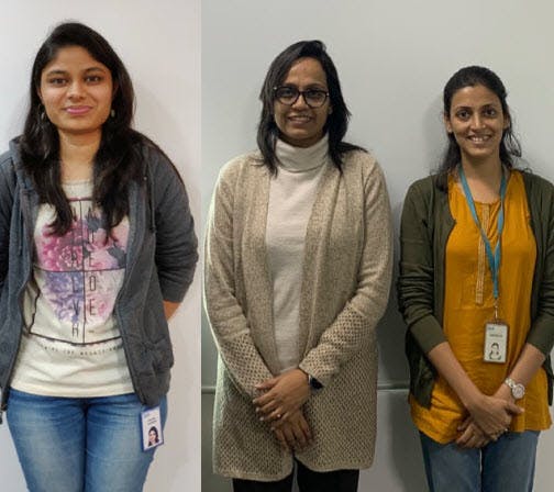 Three female IBM research scientists stand shoulder-to-shoulder looking at the camera