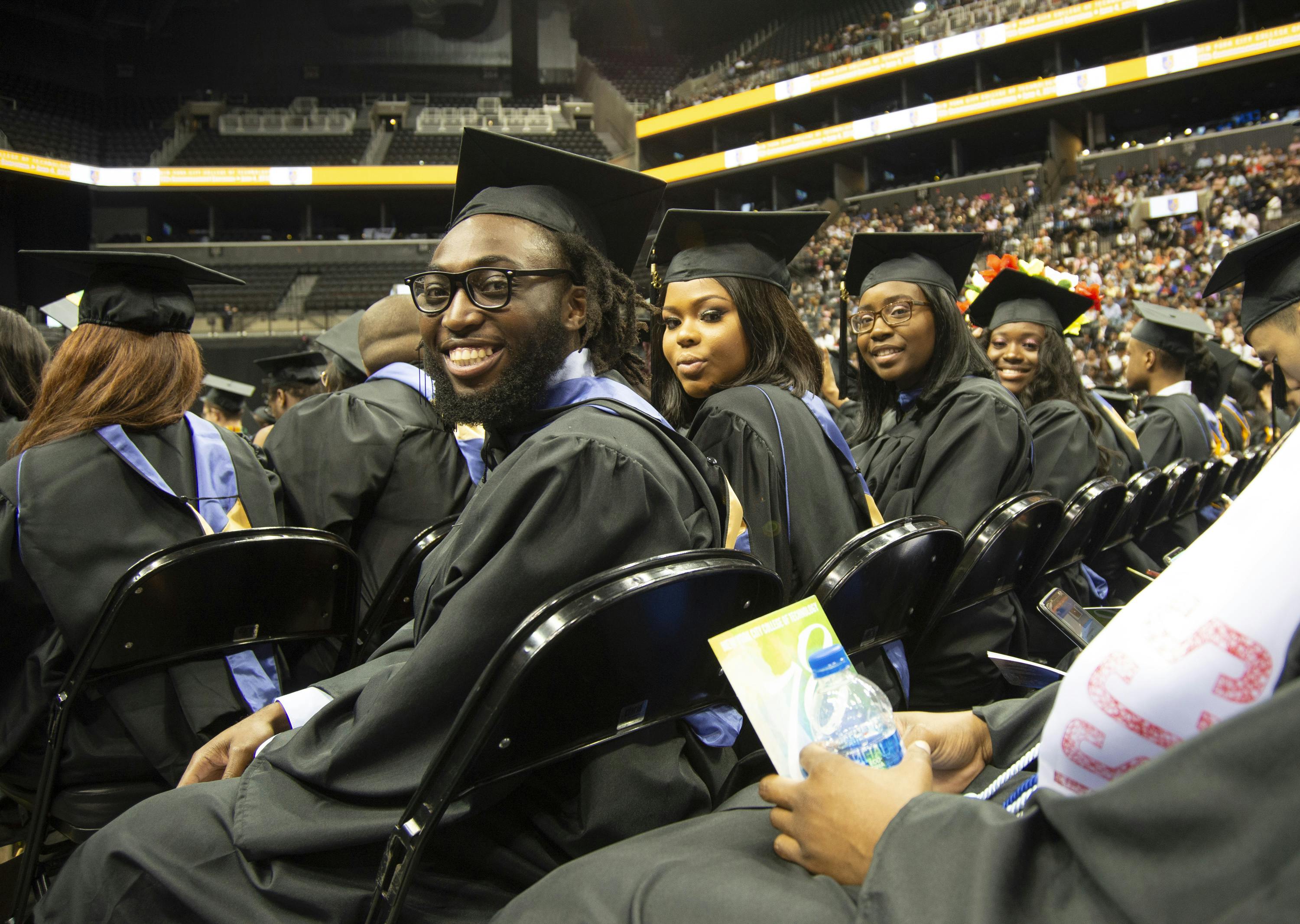 Students in caps and gowns sitting in a row at graduation