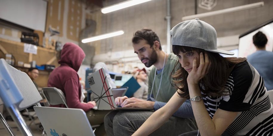 Girl working on a laptop with a lot of other developers