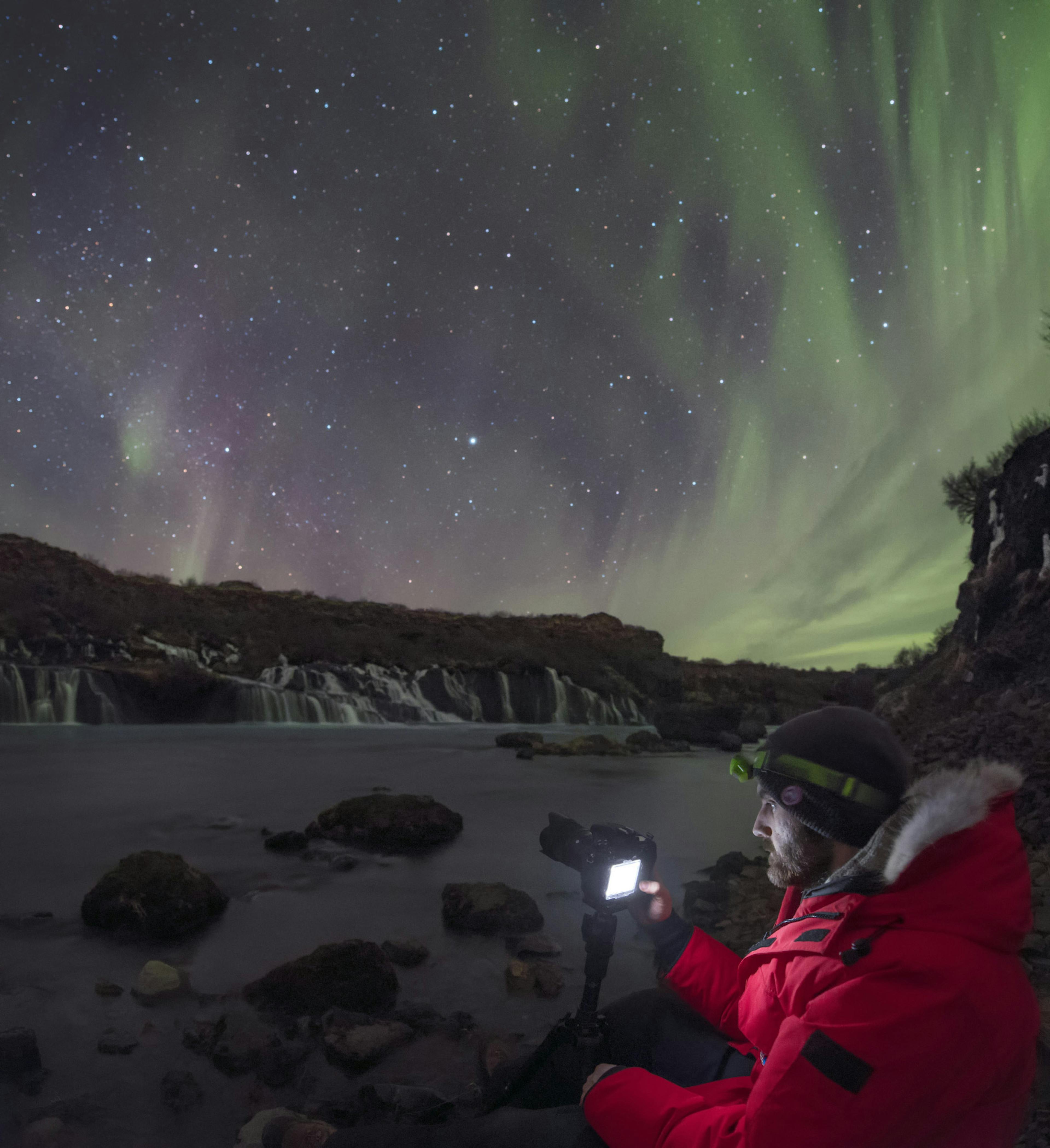 Gísli Már Árnason shooting the Northern Lights over Hraunfossar waterfalls in West Iceland. Credit: Babak Tafreshi. From the book Iceland at Night: Your Guide to Northern Lights and Stargazing in Iceland