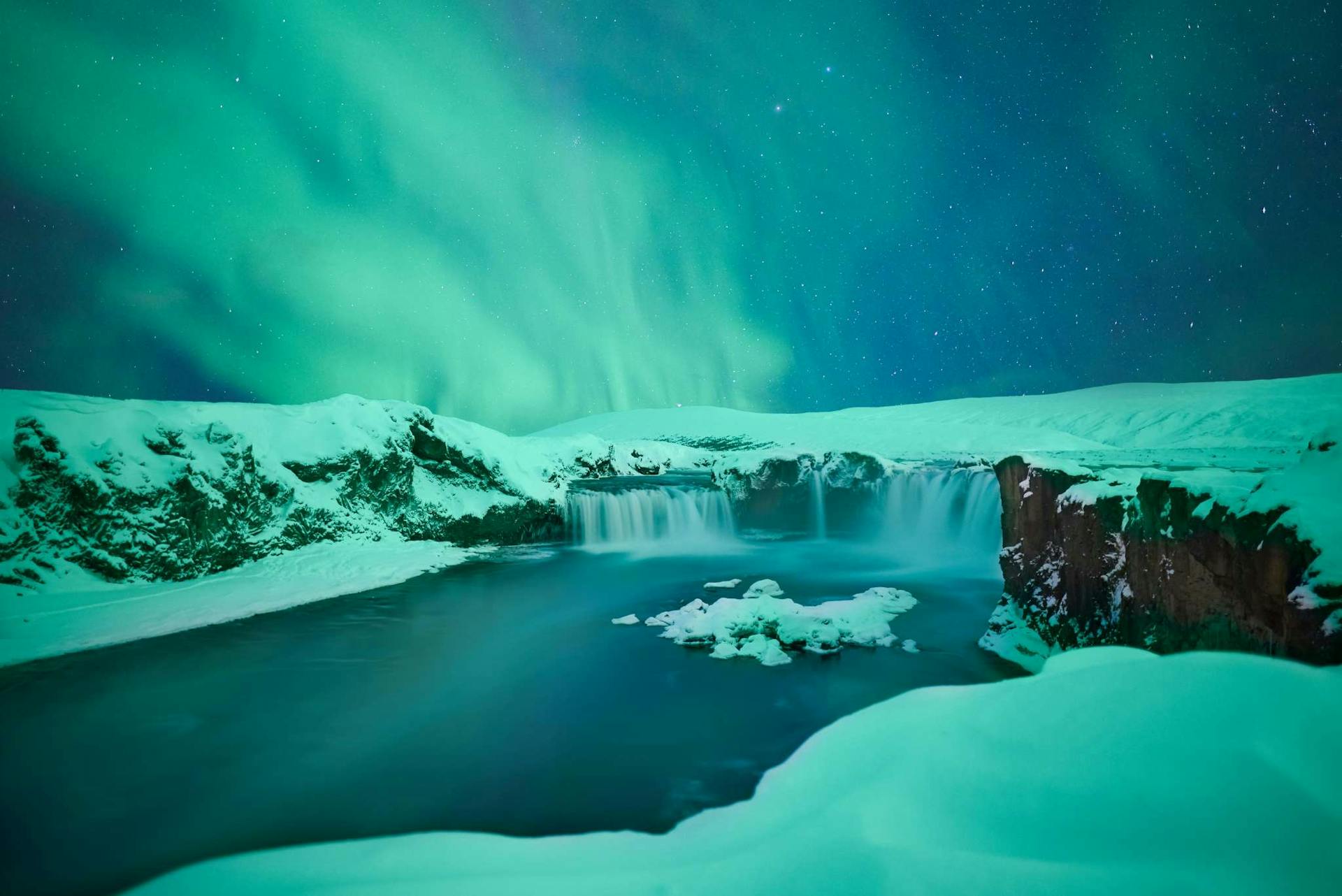 Waterfall with Northern Lights above it in Iceland