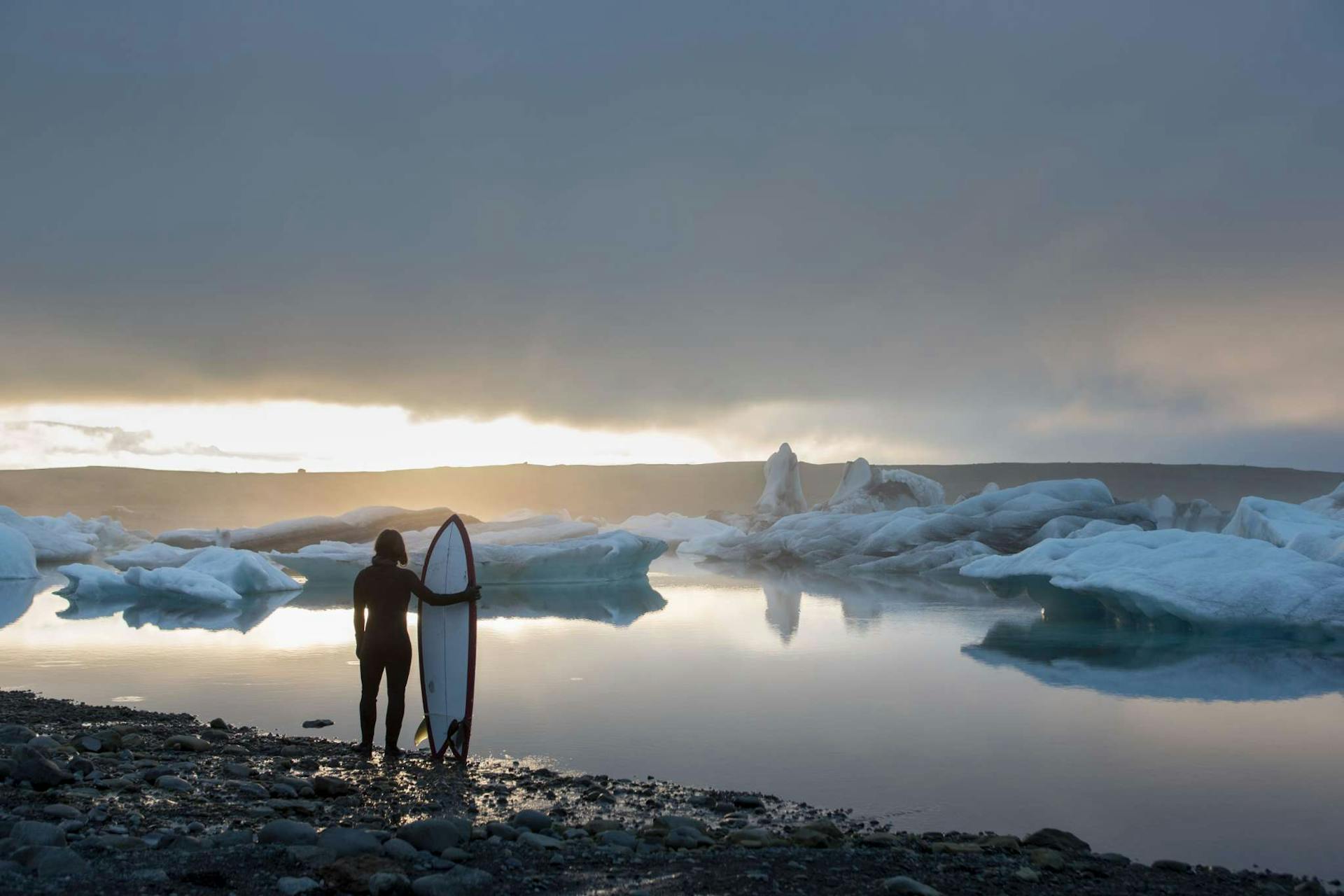 Woman with surfboard at Iceland Glacier Lagoon