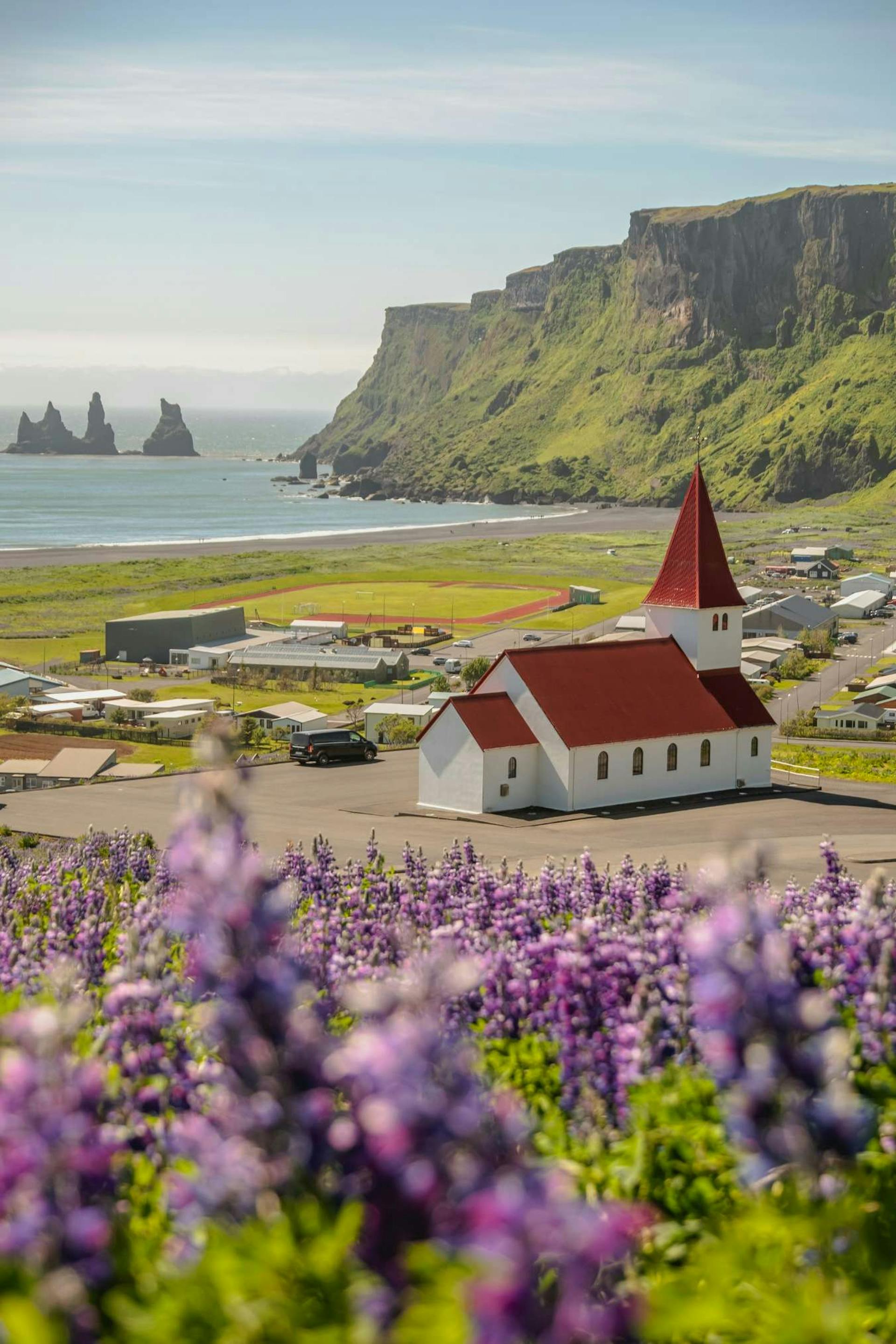 Vík church during summer with green mountains and Lupins