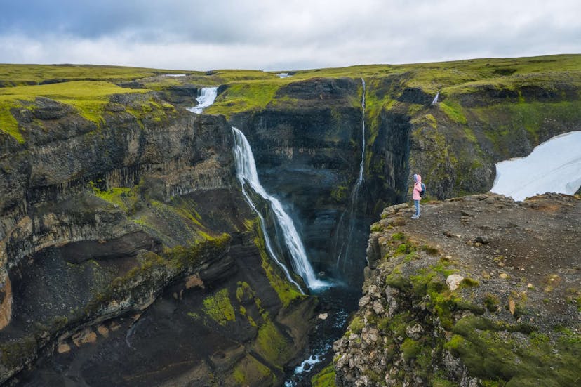 Woman hiking by a waterfall in Iceland