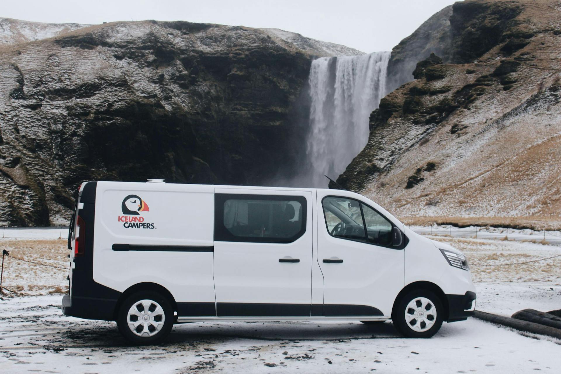 Campervan parked by Skogafoss waterfall in Iceland