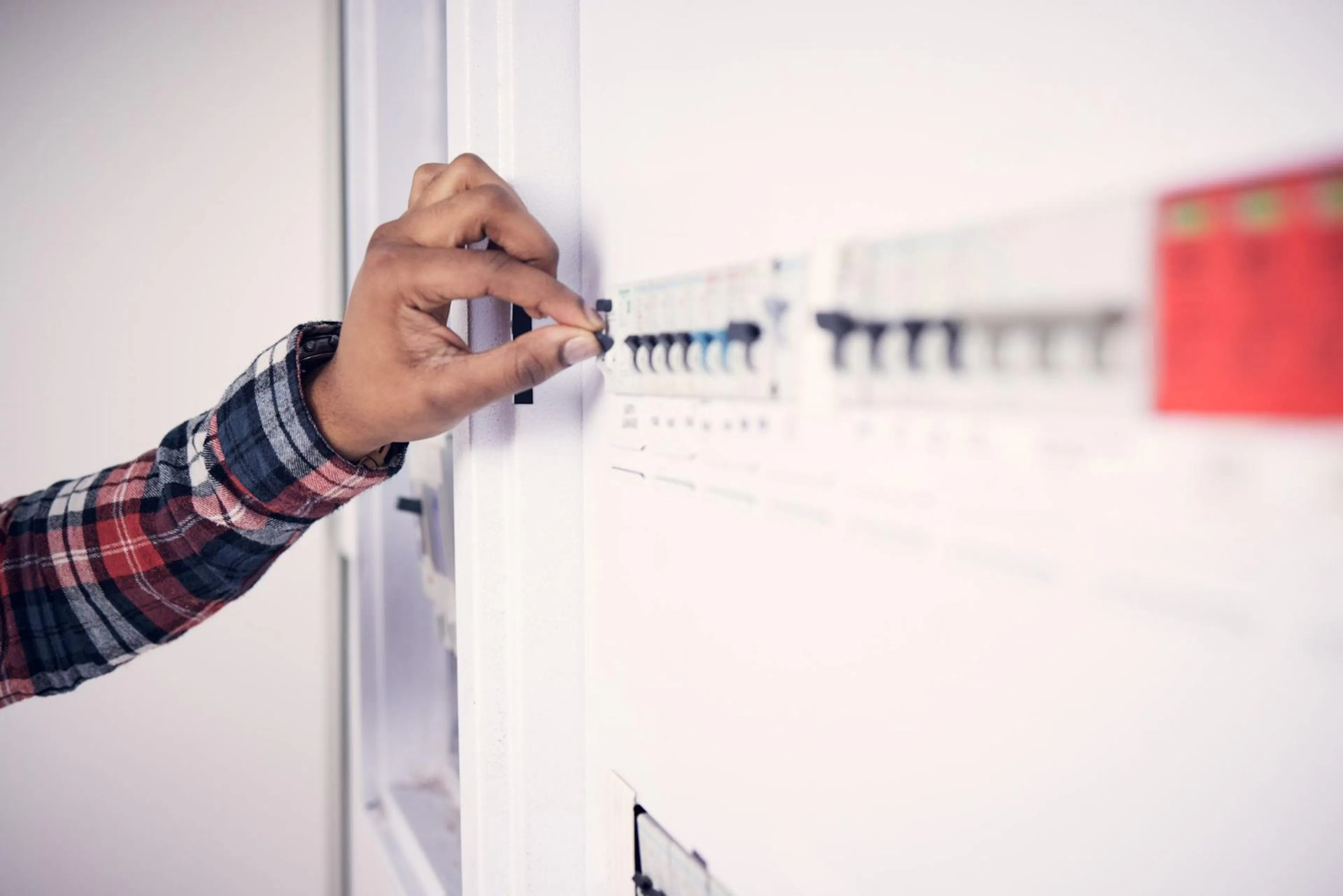 Hand switching off a circuit breaker on a home switchboard