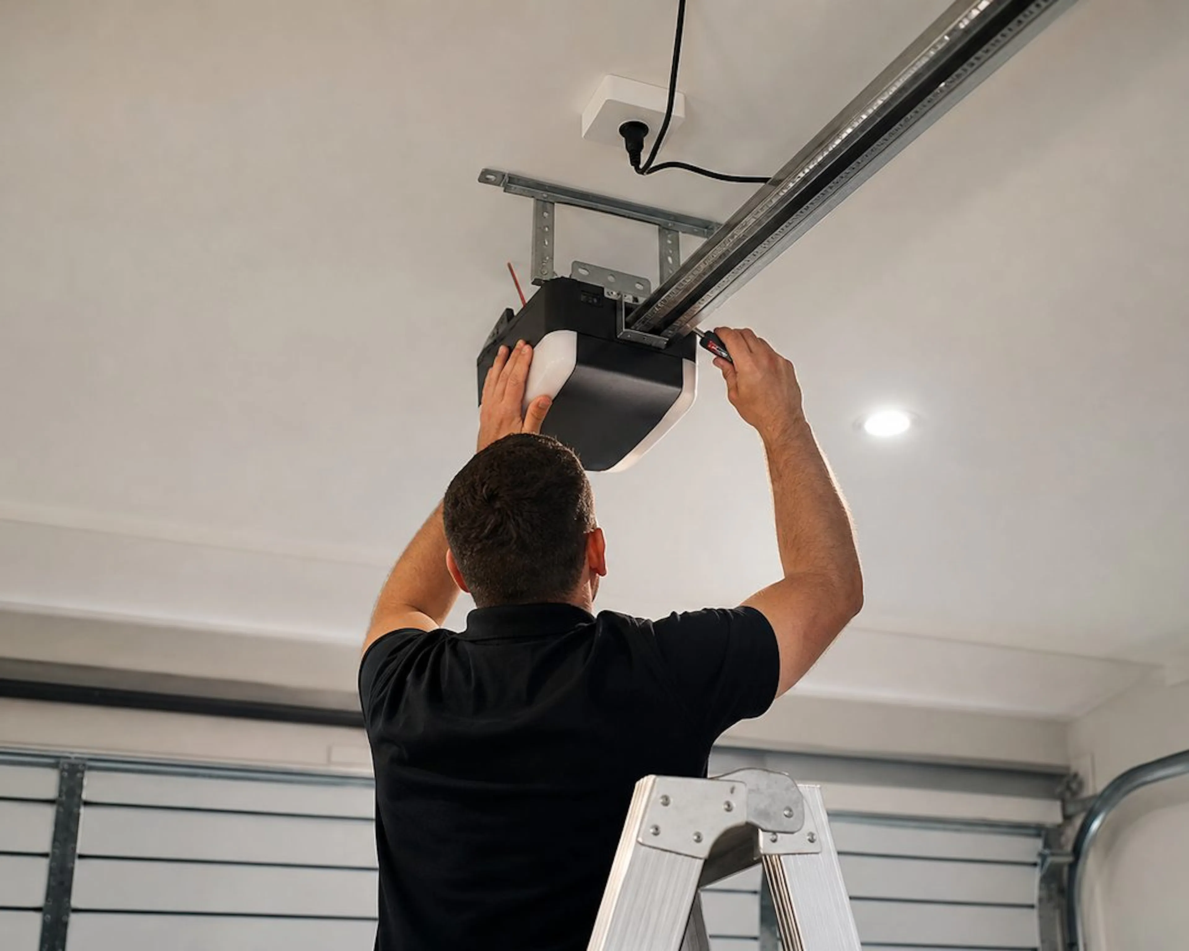 Electrician installing a garage door motor on the ceiling