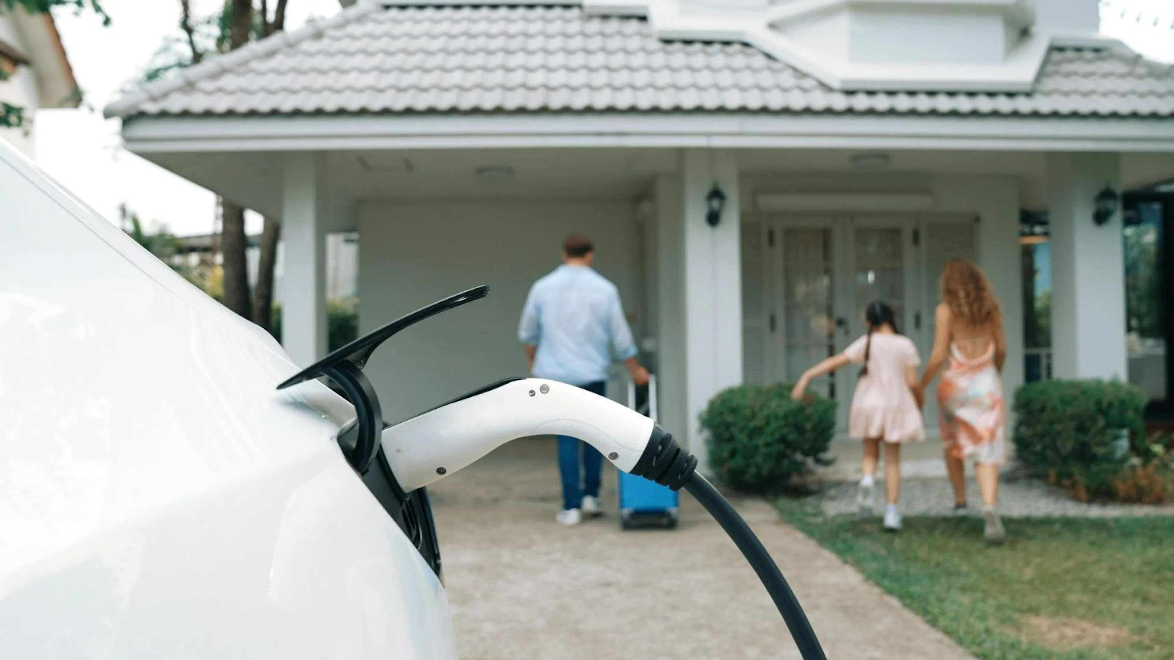 Electric car charging outside a family home as the family walks to the door