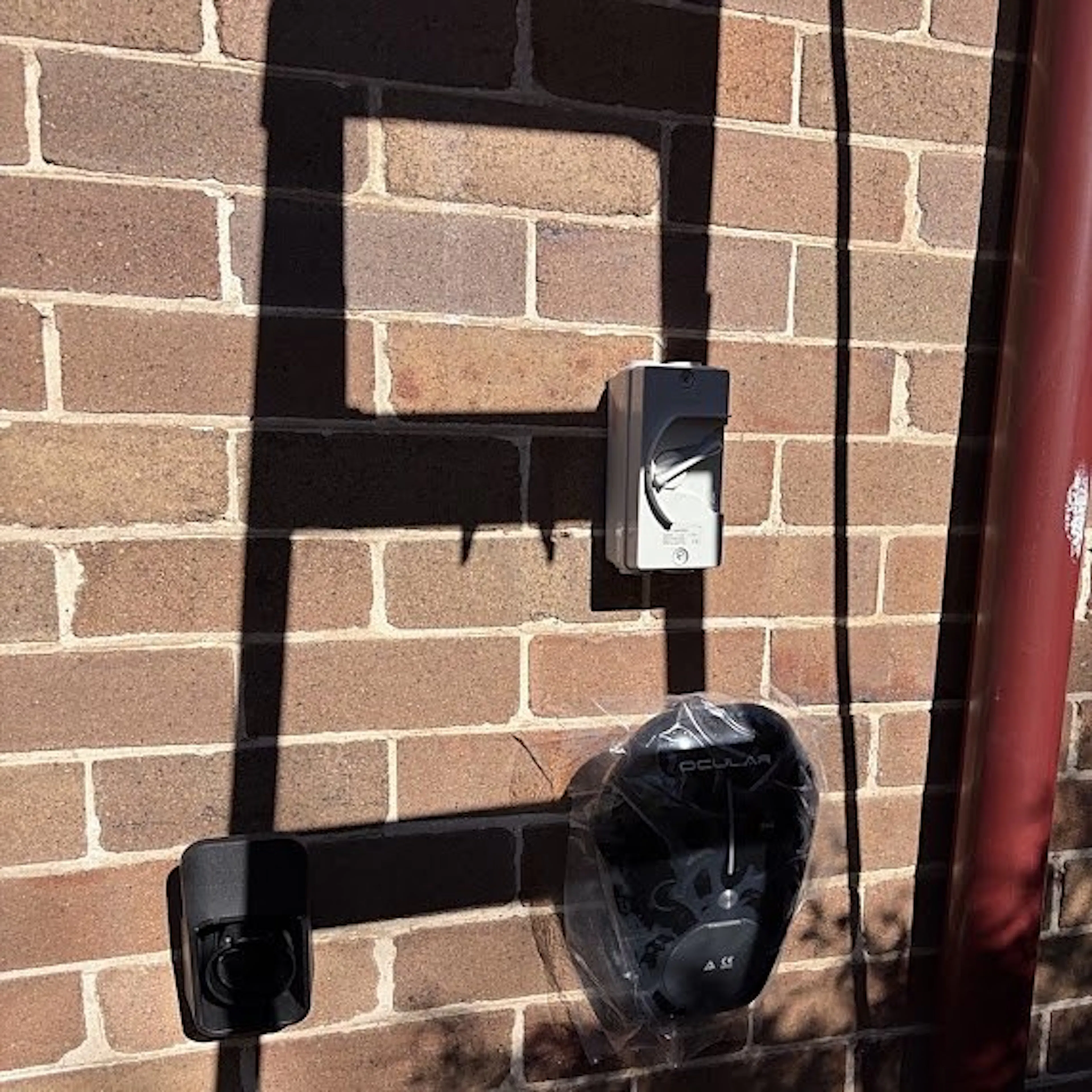Ocular EV charger and isolator on a brick wall, by Impulse Electrical Enterprise