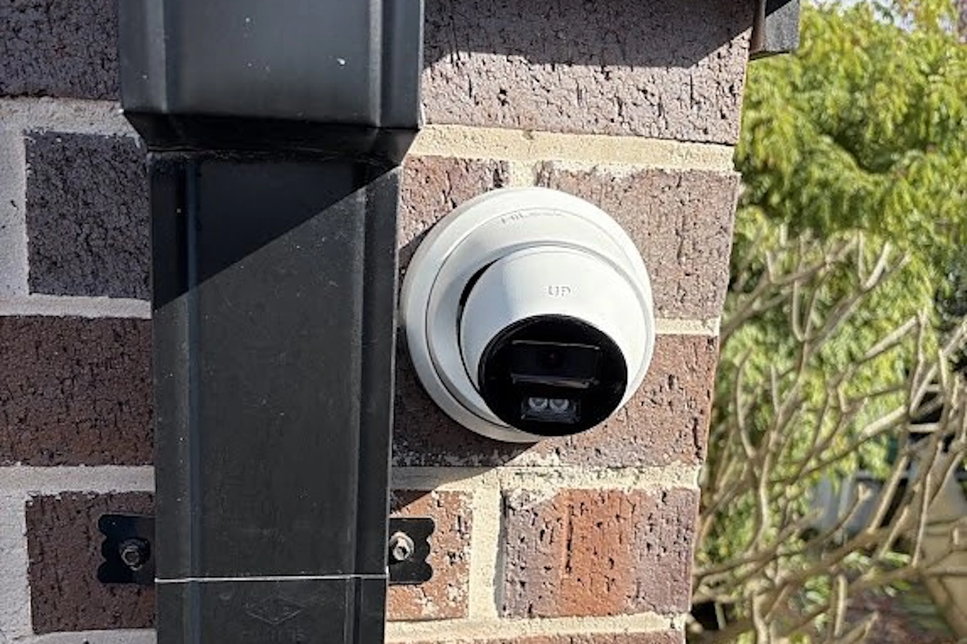 Turret CCTV camera mounted on a brick wall beside a downpipe at a Sydney home