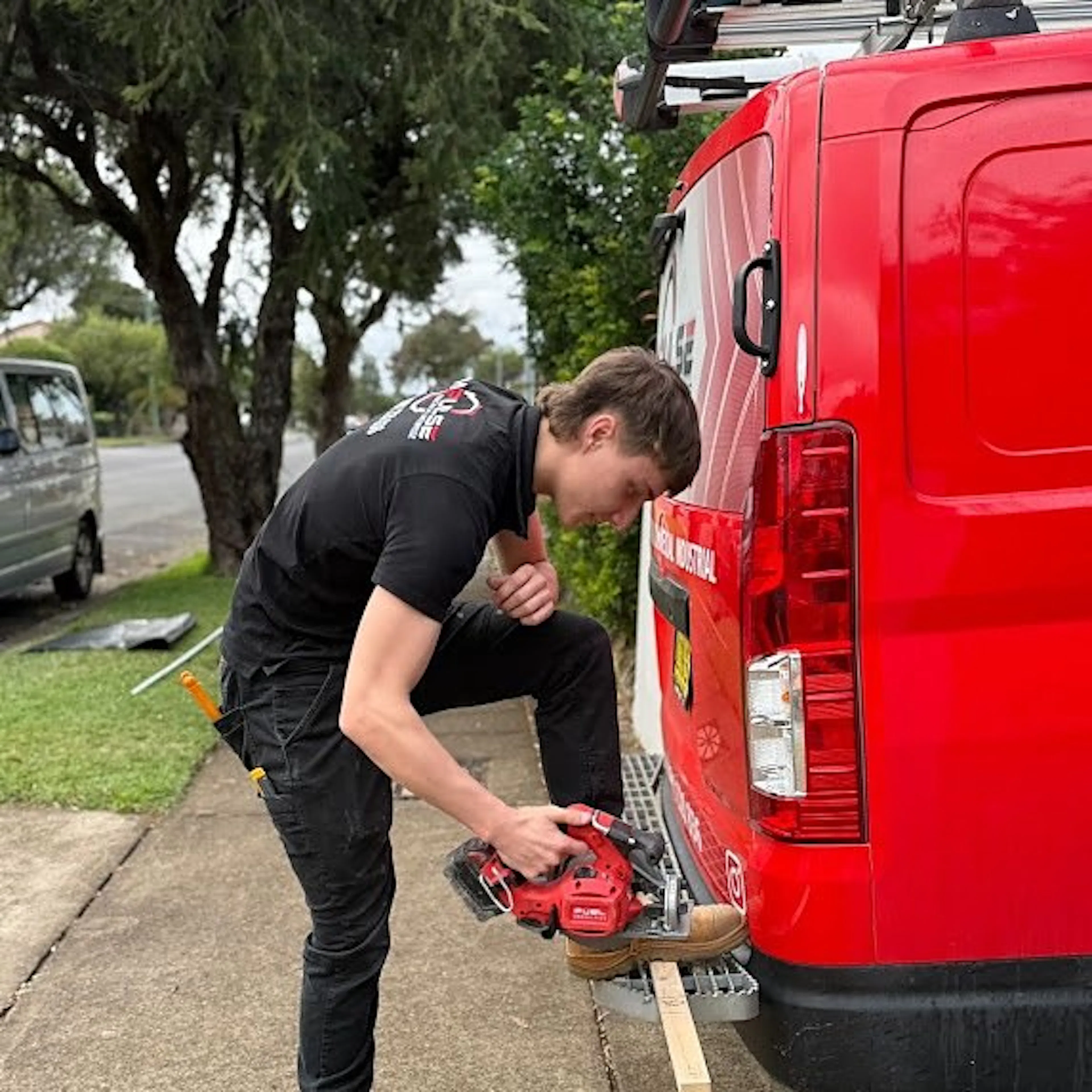 An Impulse Electrical Enterprise electrician preparing materials beside the van