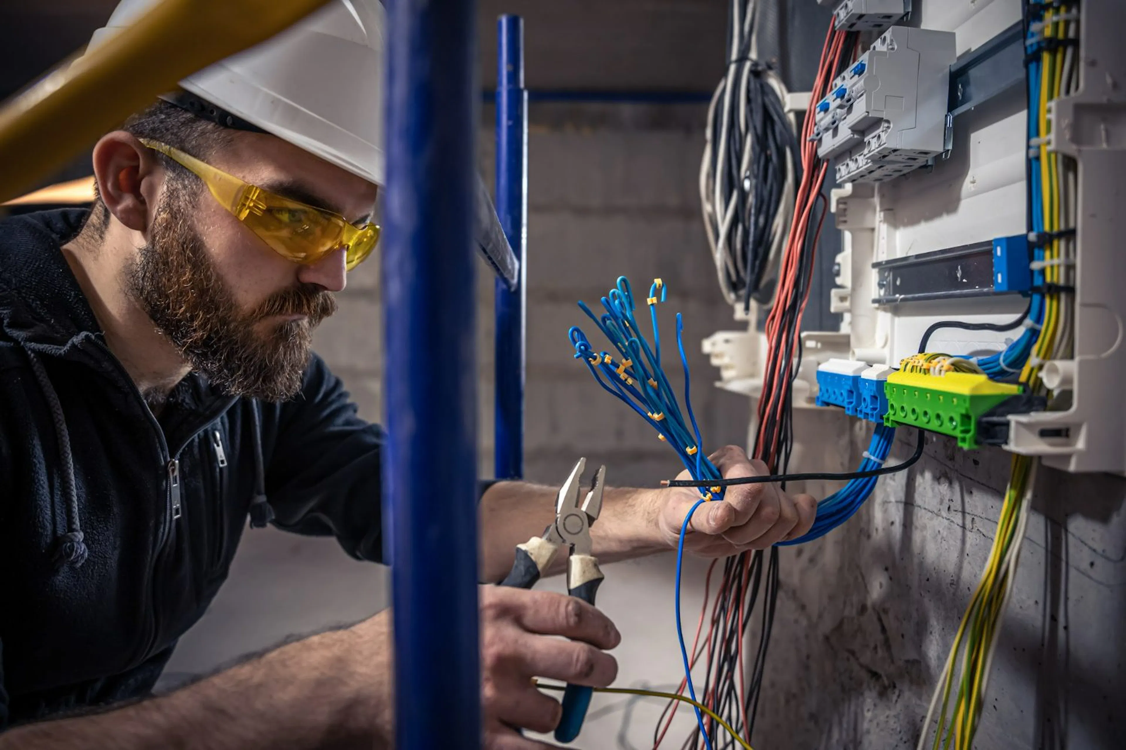 Electrician in safety glasses working on exposed wiring